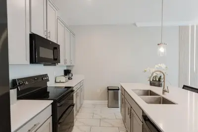 a white kitchen with a sink and a microwave at Casa 4Q c Piscina Privativa Perto da Disney in Kissimmee