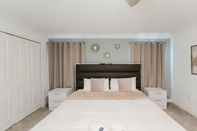 a white bedroom with a large white bed with curtains at Casa 4Q c Piscina Privativa Perto da Disney in Kissimmee