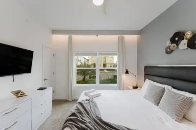 a white bedroom with a large bed and a television at Casa 4Q c Piscina Privativa Perto da Disney in Kissimmee
