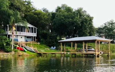 a house on the shore of a lake with a dock at Lakefront with Dock on Private Lake Florence near Montverde Academy in Montverde