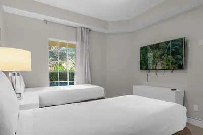 two beds in a white room with a window at 2 Bedroom Condo 6403 in Orlando