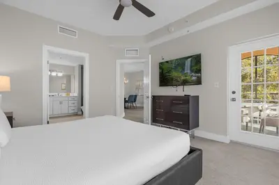 a white bedroom with a bed and a flat screen tv at 2 Bedroom Condo 6403 in Orlando