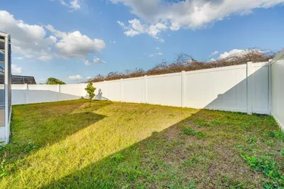 a white fence with a grassy yard next to it at 8 Mi to Disney Parks Poolside Paradise! in Kissimmee
