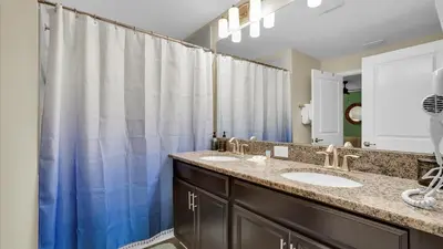 a bathroom with two sinks and a blue shower curtain at GAS3070 in Kissimmee