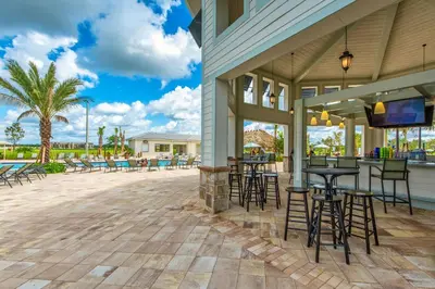 a patio with tables and chairs and a bar at Spacious 4BR Townhome with Pool at Storey Lake in Kissimmee