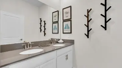 a bathroom with two sinks and three pictures on the wall at QTS4361 in Kissimmee