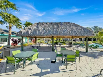 a patio with tables and chairs and a thatch roof at QTS4361 in Kissimmee