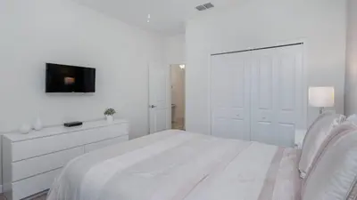 a white bedroom with a bed and a tv at KCC4741 in Kissimmee