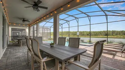 a screened in porch with a wooden table and chairs at PGD4169 in Kissimmee