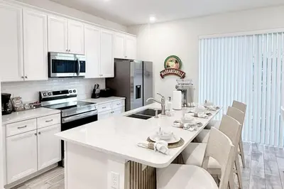 a kitchen with white cabinets and a table with chairs at Just Lauched - Luxury & Cozy 3BR near Disney-Margaritaville in Orlando