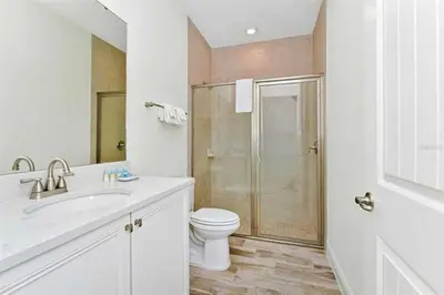 a white bathroom with a toilet and a shower at Just Lauched - Luxury & Cozy 3BR near Disney-Margaritaville in Orlando