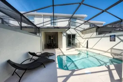 a house with a swimming pool and two black chairs at casa 4Q com piscina Mickey & Star Wars! in Kissimmee