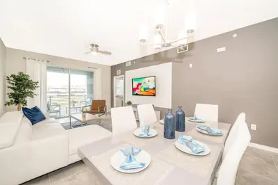 a living room with a white couch and a table and chairs at Aconchegante 2Q no Storey Lake – 10 min da Disney! in Kissimmee