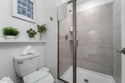 a white bathroom with a shower and a toilet at Family Mickey & Star Wars - FREE Heated Pool in Kissimmee
