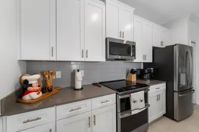 a kitchen with white cabinets and stainless steel appliances at Family Mickey & Star Wars - FREE Heated Pool in Kissimmee
