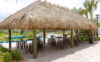 a group of tables and chairs under a straw umbrella at Villa Kerpen - Storey Lake in Kissimmee