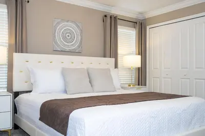 a white bedroom with a large white bed with pillows at Villa Smile, Storey Lake in Kissimmee