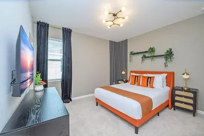 a bedroom with a bed and a flat screen tv at Brand New 12BR Disney Mansion Pool Spa Game Room in Kissimmee