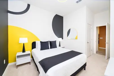 a bedroom with a bed and a yellow and white wall at Brand New 12BR Disney Mansion Pool Spa Game Room in Kissimmee