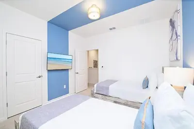 a bedroom with two beds and a blue wall at Brand New 12BR Disney Mansion Pool Spa Game Room in Kissimmee