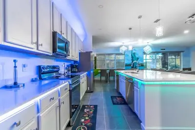 a large kitchen with white cabinets and blue walls at Brand New 15BR Mansion Pool Spa Close to Disney in Kissimmee