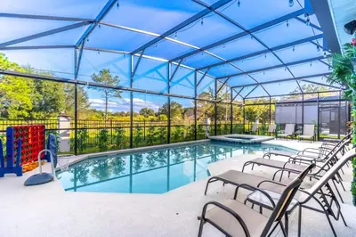 a swimming pool with chairs and a glass roof at Brand New 15BR Mansion Pool Spa Close to Disney in Kissimmee