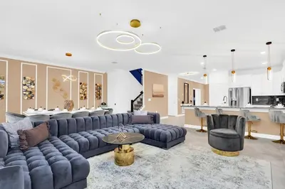 a living room with a blue couch and a kitchen at Brand New High End 9BR Villa in Storey Lake Resort in Kissimmee