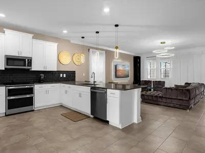 a kitchen with white cabinets and a living room at Brand New High End 9BR Villa in Storey Lake Resort in Kissimmee