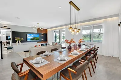 a dining room and living room with a table and chairs at Brand New Luxury 9BR Villa Pool Spa Game Room in Kissimmee