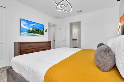 a bedroom with a large bed with a yellow blanket at Brand New Luxury 9BR Villa Pool Spa Game Room in Kissimmee