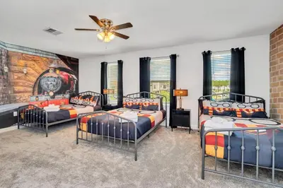a room with three beds and a clock on the wall at Brand New Storey Lake 10 Bedroom Villa with Pool in Kissimmee