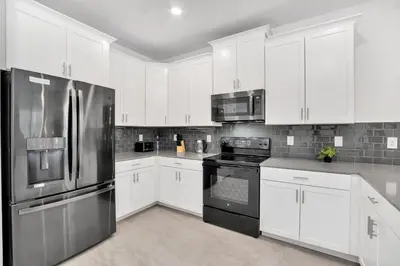 a kitchen with white cabinets and stainless steel appliances at Brand New Storey Lake 10 Bedroom Villa with Pool in Kissimmee