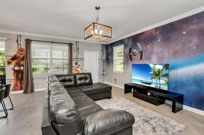 a living room with a leather couch and a flat screen tv at Brand New Storey Lake 8BR Villa with Lake View in Kissimmee