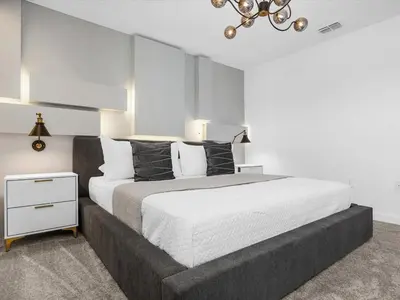a bedroom with a large bed and a chandelier at Brand New Storey Lake 9BR Villa Summer Kitchen in Kissimmee