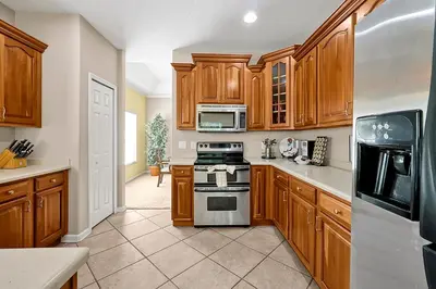 a kitchen with wooden cabinets and a stove top oven at 11326 CYPRESS TRAIL DRIVE ORLANDO 3BED in Orlando
