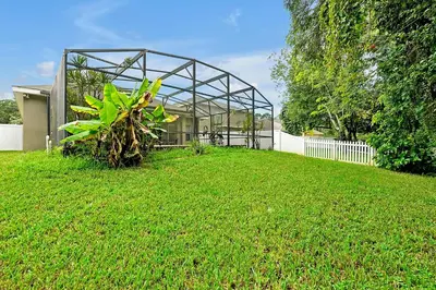 a green house with a plant in the yard at 11326 CYPRESS TRAIL DRIVE ORLANDO 3BED in Orlando