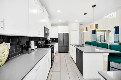 a kitchen with white cabinets and black appliances at Dazzling 5BR Villa in Storey Lake with Pool & Spa 1528 in Kissimmee