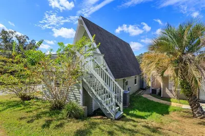 a house with a staircase leading up to a house with palm trees at Hope House- Vacation Village 1 Bedroom with Loft in Clermont