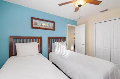 two beds in a bedroom with blue walls and a ceiling fan at CUP8931 in Kissimmee