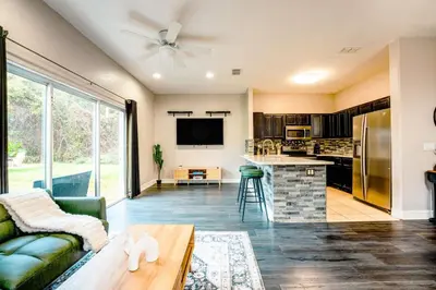 a living room with a couch and a kitchen at Full House HotTub Mins to UCF in Bithlo