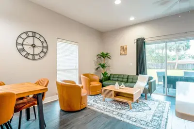 a living room with a couch and a table and a clock at Full House HotTub Mins to UCF in Bithlo