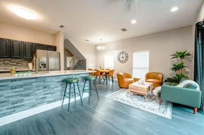a kitchen and living room with a counter and chairs at Full House HotTub Mins to UCF in Bithlo