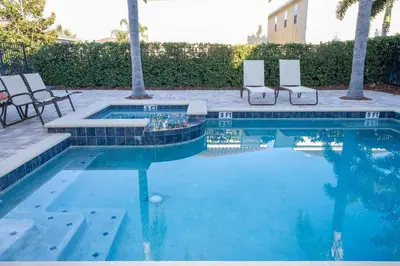 a swimming pool with two chairs and a table at Classic 8bd house - Encore Reunion Close to Disney in Orlando