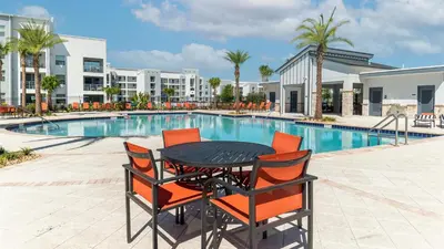 a black table with orange chairs next to a swimming pool at PXC3111-202 in Kissimmee