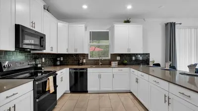 a kitchen with white cabinets and black appliances at OMW2718 in Kissimmee