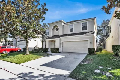 a white house with a car parked in the driveway at TT7752 Windsor Hills Resort 6br in Orlando