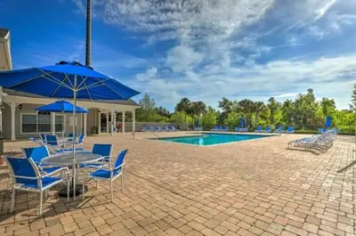 a patio with a table and chairs and a pool at Cozy condo Just a few minutes from Disney in Kissimmee