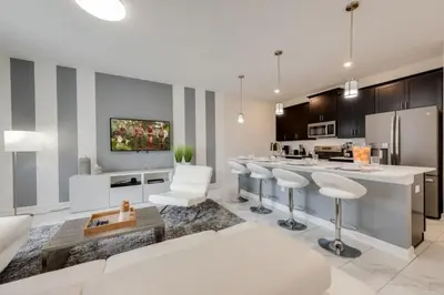 a living room with a kitchen with bar stools at 4QT Elegante Casa c/ Piscina – 10 Min da Disney! in Kissimmee
