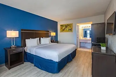 a bedroom with a large bed with a blue wall at Palm Tree Inn Altamonte Springs Orlando in Orlando
