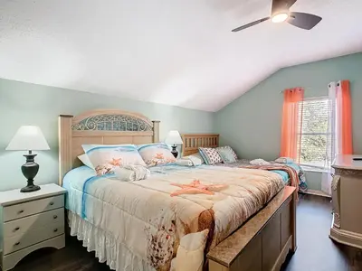 a bedroom with a large bed and a ceiling fan at Group retreat w pool, spa & BBQ in Orlando